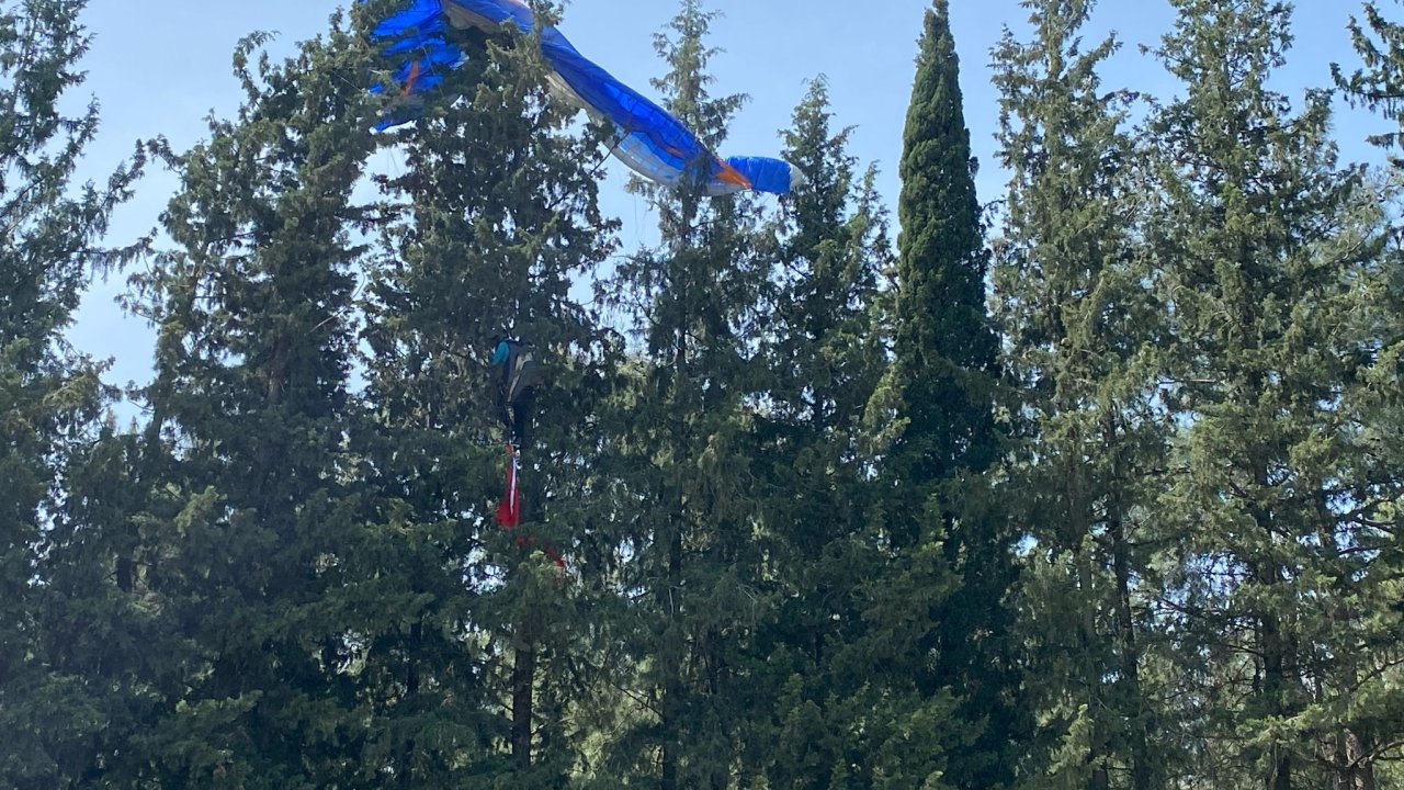 Gösteri uçuşu yapan paraşüt pilotu ağaçlara takıldı
